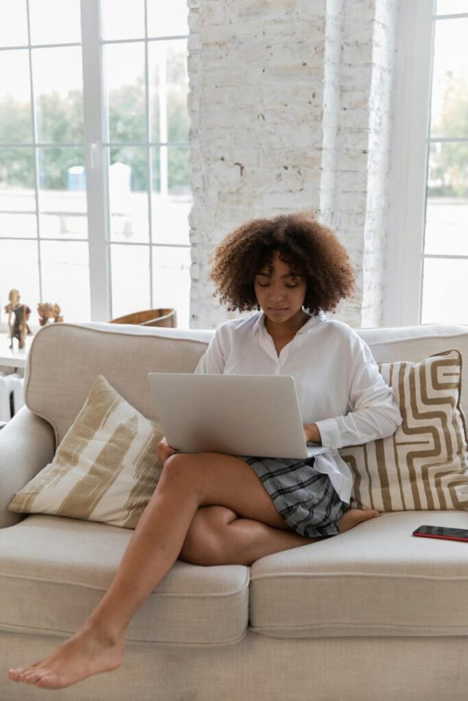 A woman on a couch with her laptop doing digital journaling.
