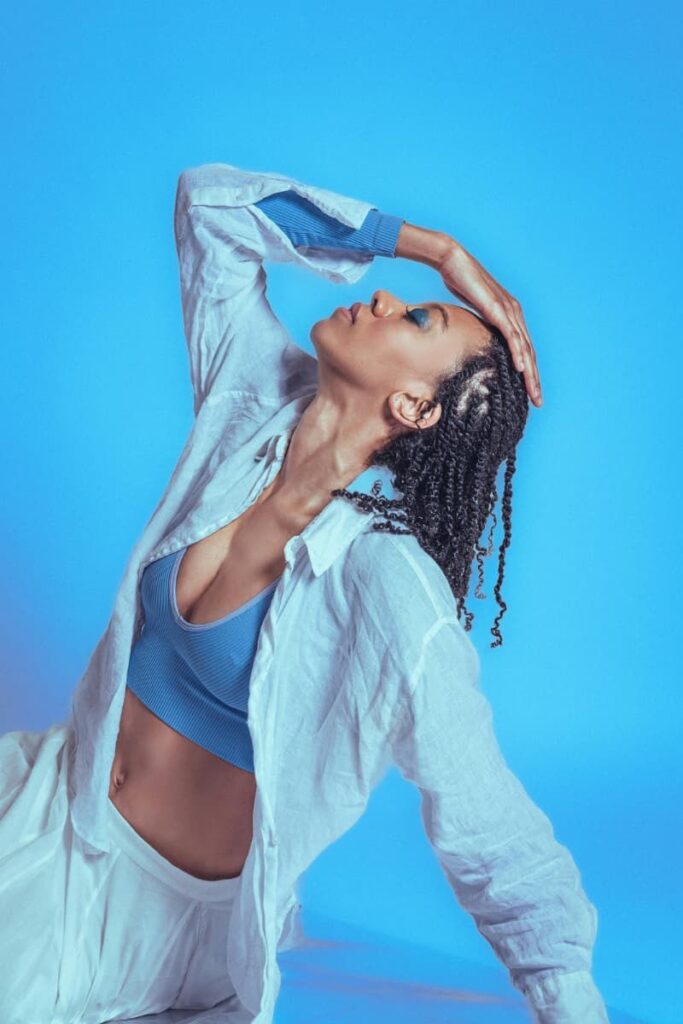 A woman wearing a while shirt and bottoms and a blue tank top representing a balance of feminine and masculine energy traits.