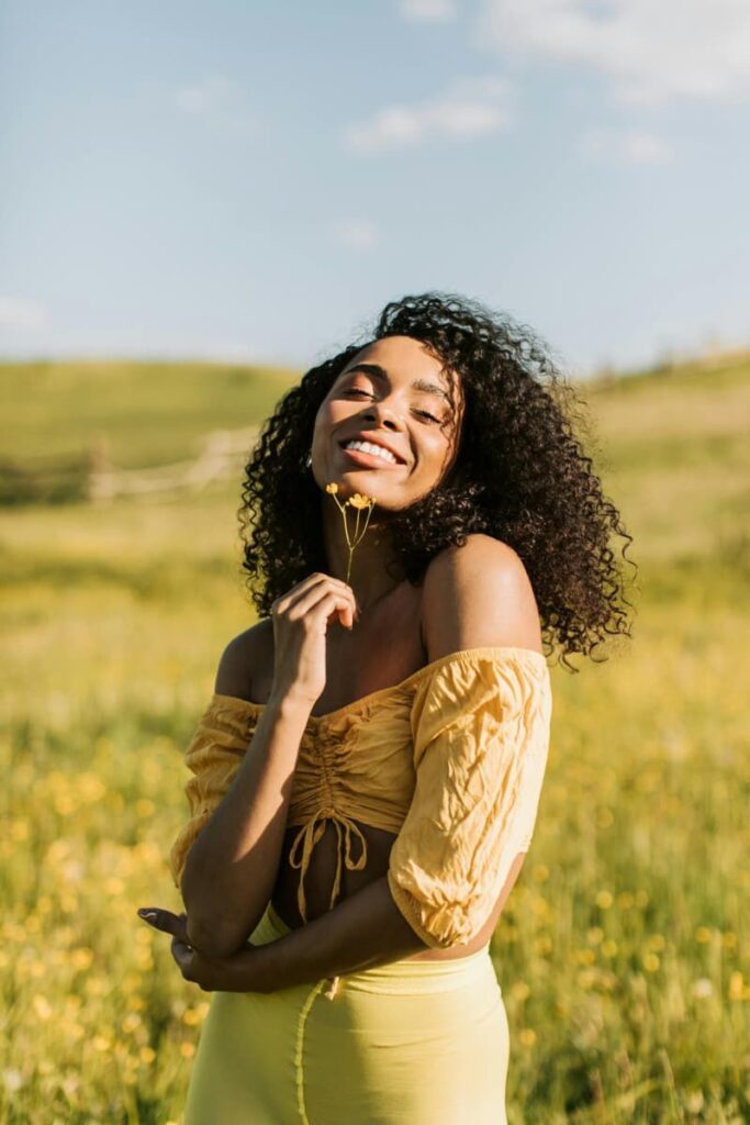 Image of a happy woman wearing yellow in a field indicating the benefits of stream-of-consciousness journaling .