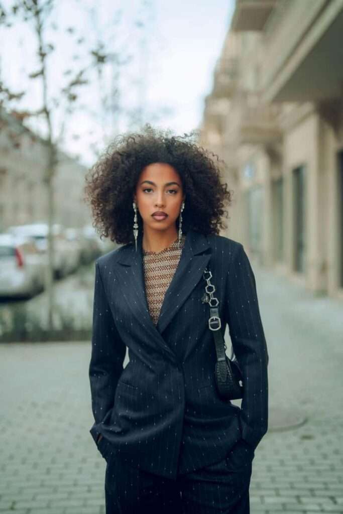 Woman in a black suit on a street looking and feeling like a boss because of the self-improvement tips for women she has used to grow 
