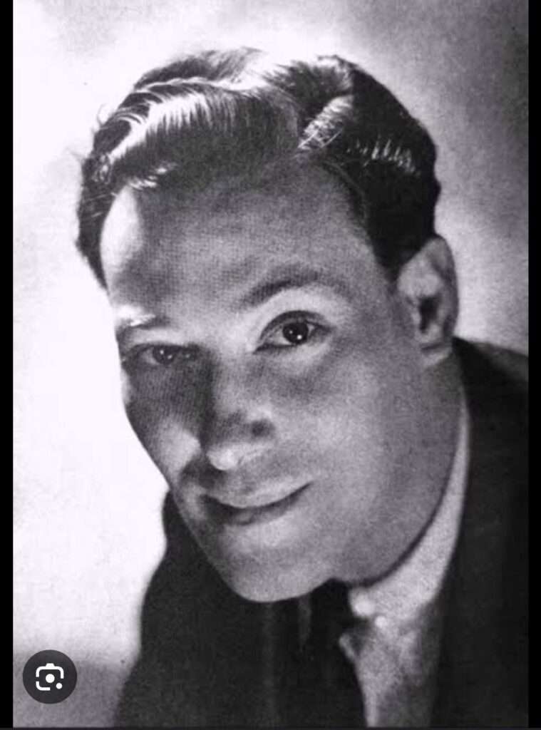 A screenshot image of Neville Goddard posing in a suit.