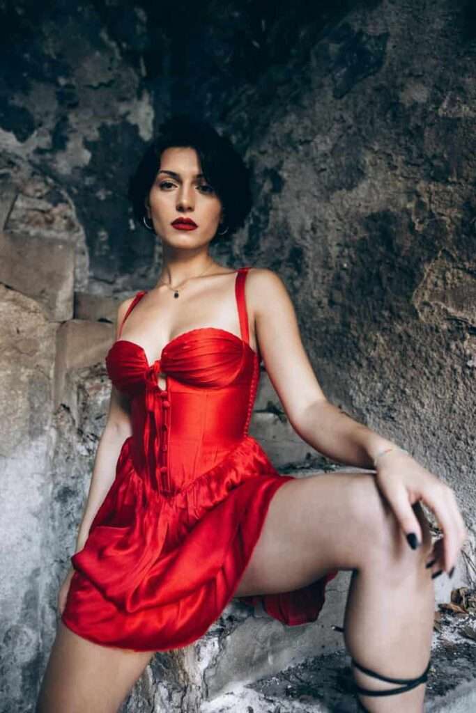 Image of a woman in a red dress and red lipstick in her dark, divine feminine energy.