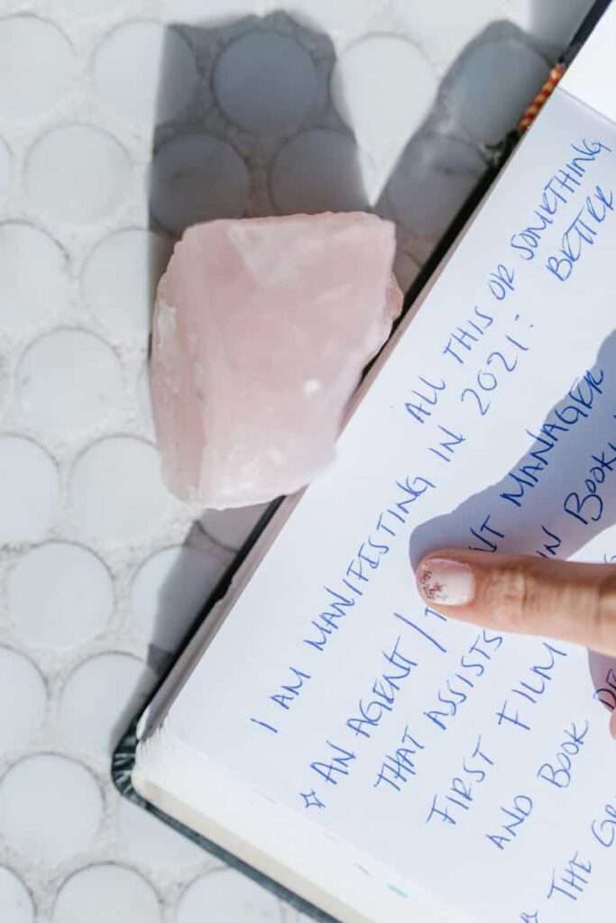 Image of a manifestation script journal and a rose quartz.