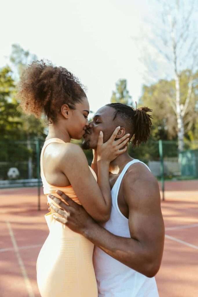 Image of a black couple on a basketball pitch kissing representing the benefits of using feminine energy in dating.