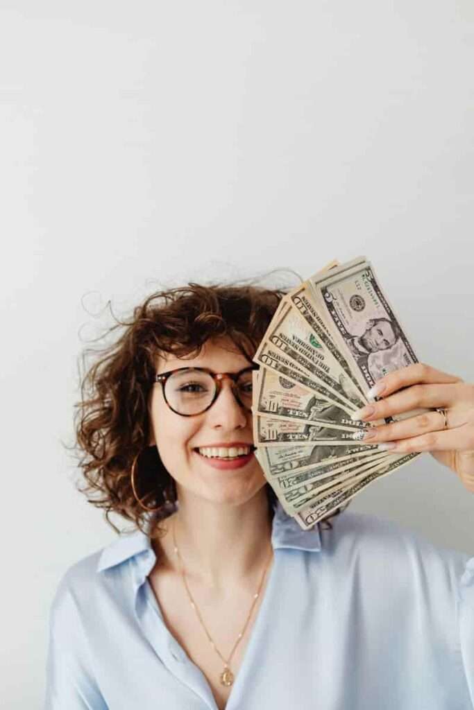 Image of a woman holding a wand of cash representing abundance.